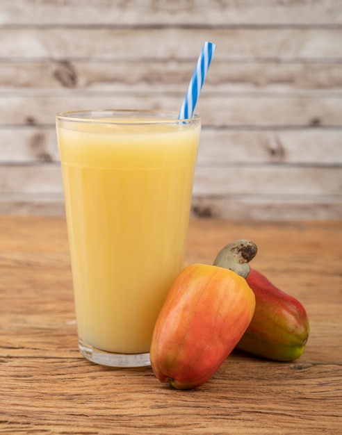 Cashew-sap in een glas met fruit over houten tafel.