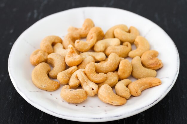 Cashew on white plate on black background