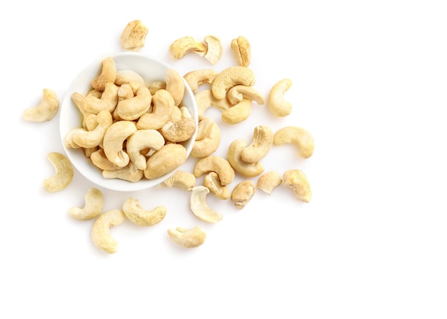 Cashewnoten in een kleine kom op wit wordt geïsoleerd