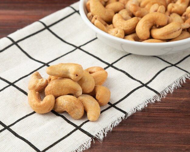 Cashewnoten in tafelkleed op houten tafel, gezonde snack, vegetarisch eten.