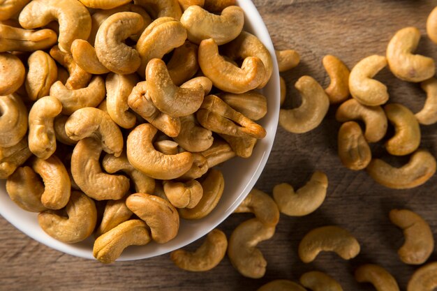 Cashewnoten in witte kom op houten achtergrond