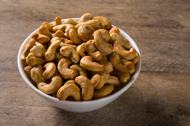 Cashewnoten in witte kom op houten achtergrond