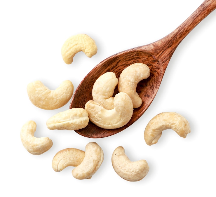 Photo cashews in a wooden spoon on a white. the view from the top.