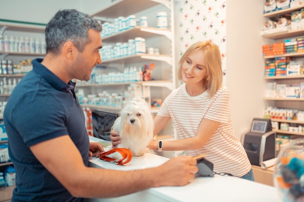 Cashier giving white fluffy dog to her new owner