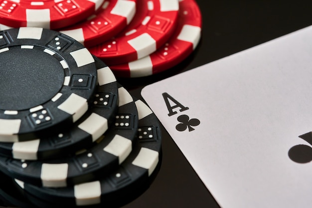 Casino chips and playing cards on dark reflective background