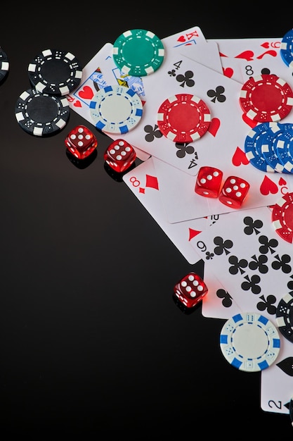 Casino chips playing cards and dices on dark reflective background