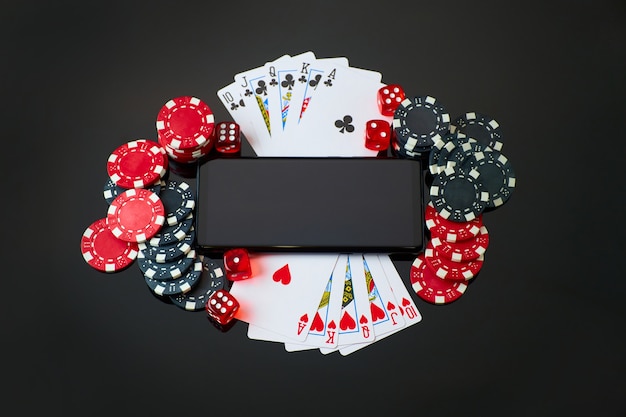 Casino chips playing cards dices and mobile phone on dark reflective background