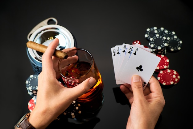 Fiches del casinò giocando a carte bicchiere di whisky e dadi su sfondo riflettente scuro dark