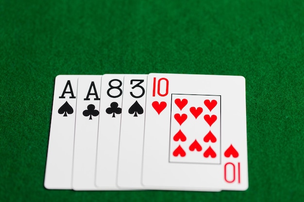 casino, gambling, games of chance, hazard and entertainment concept - poker hand of playing cards on green cloth