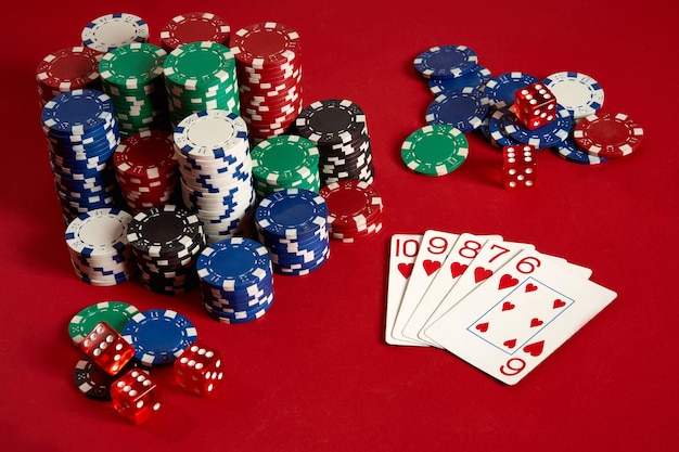 カジノギャンブルポーカー機器とエンターテインメントの概念-赤い背景のトランプとチップのクローズアップ。ストレートフラッシュ。カジノの背景。スペースをコピーします。静物