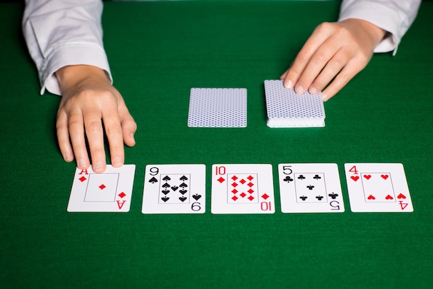 casino, gambling, poker, people and entertainment concept - close up of holdem dealer hands with playing cards