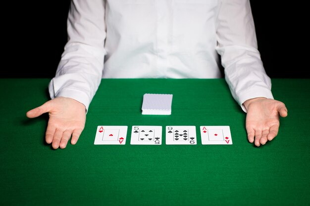 casino, gambling, poker, people and entertainment concept - close up of holdem dealer with playing cards