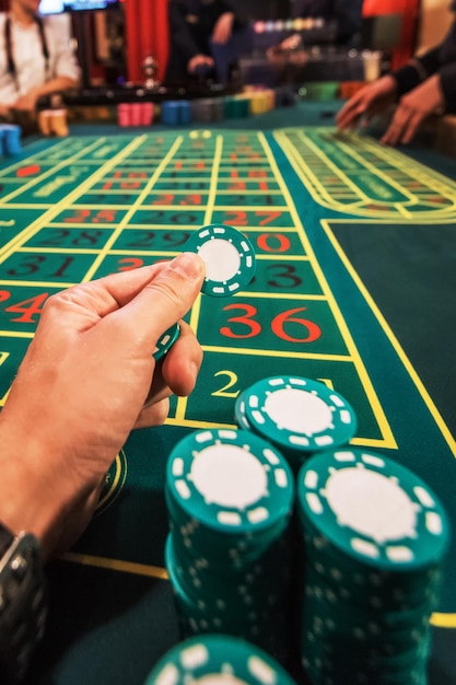 Casino gokken en entertainment concept mannenhand met stapel pokerfiches op een groene tafel backg