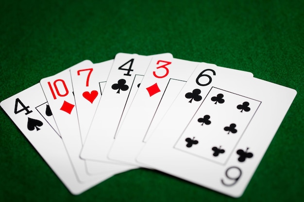 casino, gokken, kansspelen, gevaar en entertainmentconcept - pokerhand van speelkaarten op groene doek