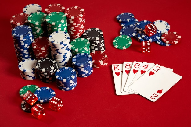 Casino gokken poker apparatuur en entertainment concept - close-up van speelkaarten en chips op rode achtergrond. Doorspoelen. Casinoachtergrond. Ruimte kopiëren. Stilleven