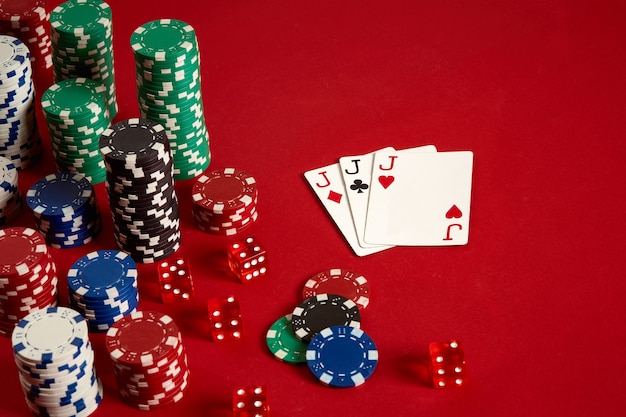 Casino gokken poker apparatuur en entertainment concept - close-up van speelkaarten en chips op rode achtergrond. Drie dezelfde. Casinoachtergrond. Ruimte kopiëren. Stilleven