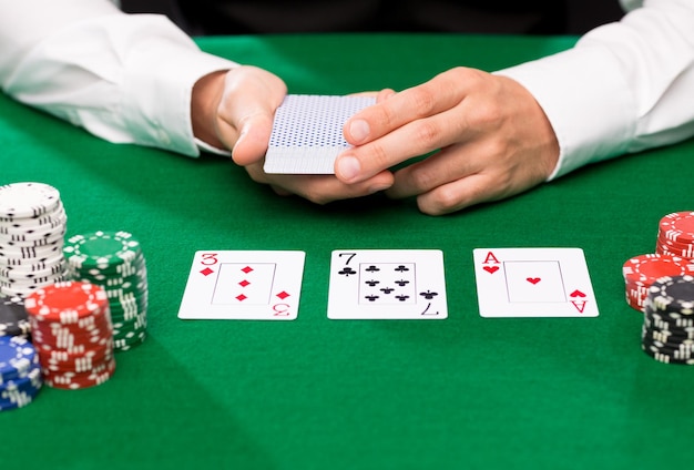 casino, gokken, poker, mensen en entertainment concept - close-up van holdem-dealer met speelkaarten en chips op groene tafel