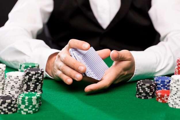 casino, gokken, poker, mensen en entertainment concept - close-up van holdem dealer schuifelende speelkaarten dek en chips op groene tafel