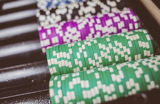 Casino kleurrijke pokerfiches liggen op de speeltafel in de stapel vintage fotoverwerking