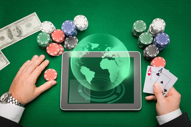 casino, online gambling, technology and people concept - close up of poker player with playing cards, tablet pc computer and chips at green casino table