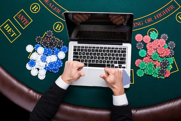 Casino, online gambling, technology and people concept - close up of poker player with playing cards