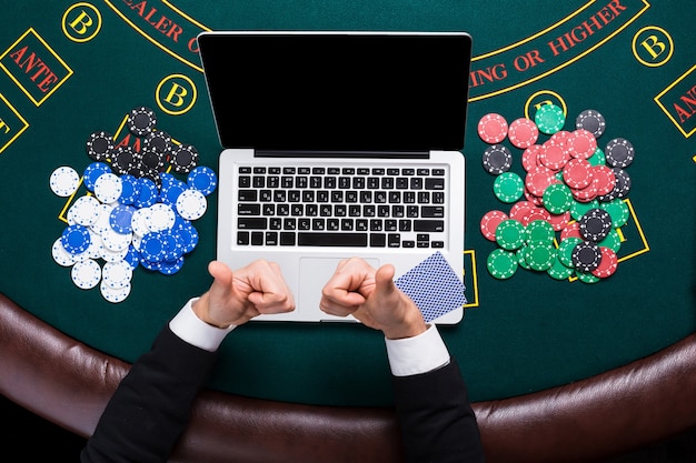 Photo casino, online gambling, technology and people concept - close up of poker player with playing cards