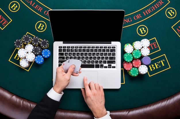 Casino, online gambling, technology and people concept - close up of poker player with playing cards