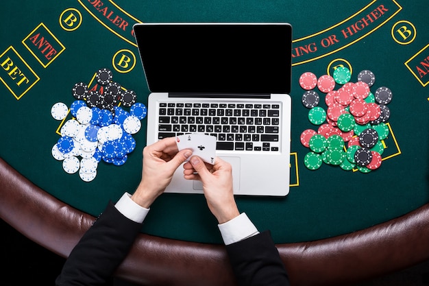 Casino, online gokken, technologie en mensenconcept - close-up van pokerspeler met speelkaarten