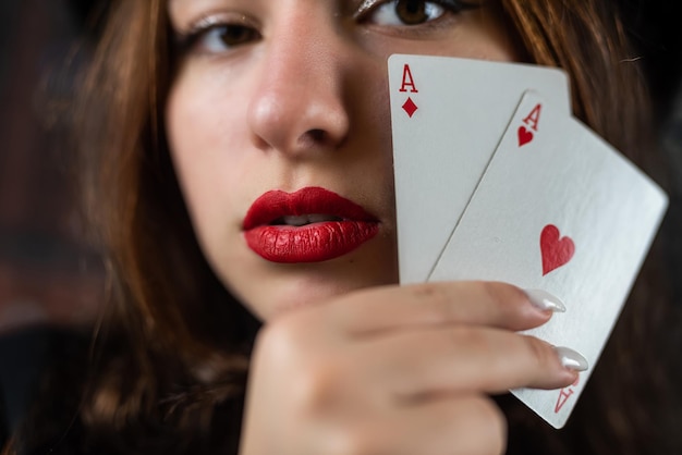 Casino woman with red lips holding ace with seductive lips and teeth face close up Poker or other games concept