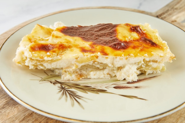 Casserole pie with cheese and sorrel on plate on light background.