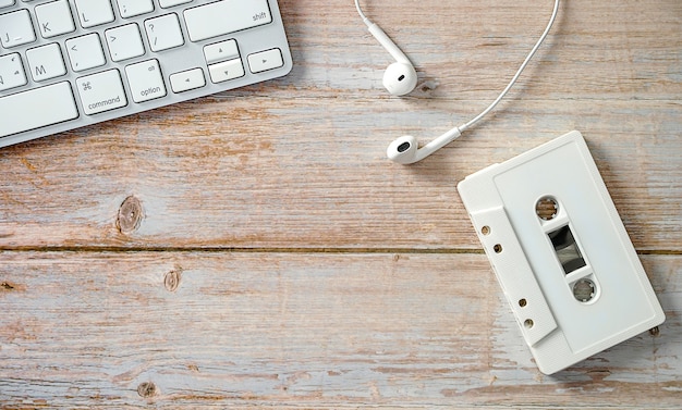 Cassette with headphones with a computer keyboard on wooden floorTechnologies of music development