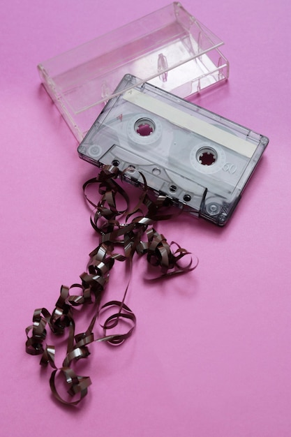 Cassette with ribbon rolled up outside on pink background