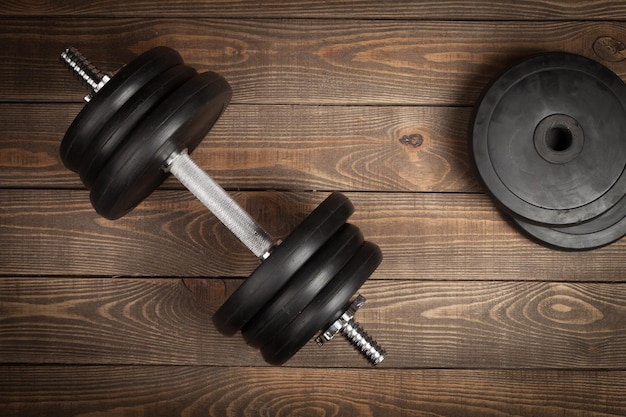 Photo cast iron dumbbell on wooden background