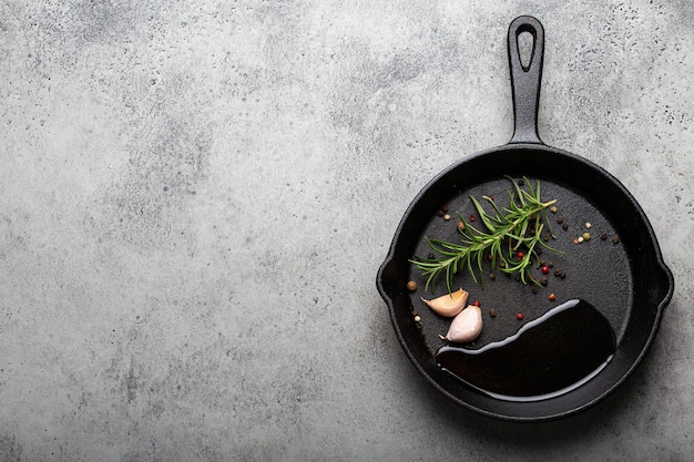 Cast iron frying pan with rosemary garlic pepper oil copy space