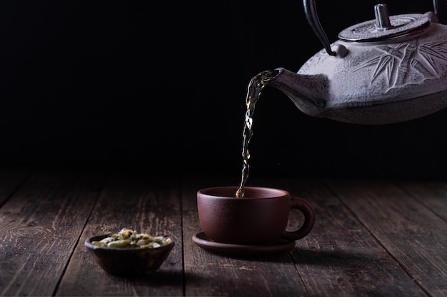 Cast-iron teapot, plum jam, dessert spoon on a dark background