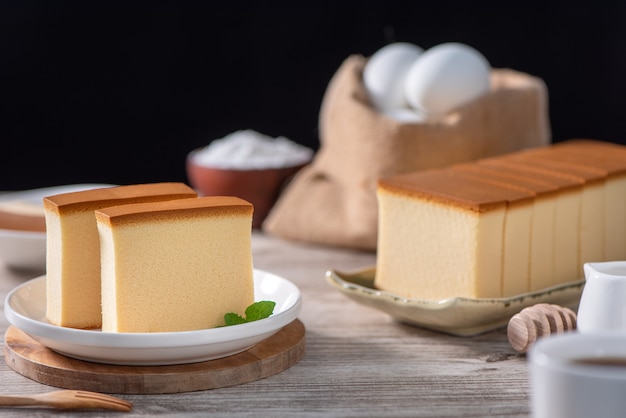 Castella (kasutera)-소박한 나무 테이블 위에 하얀 접시에 맛있는 일본 썰어 스폰지 케이크 음식, 가까이, 건강 한 식습관, 복사 공간 디자인.