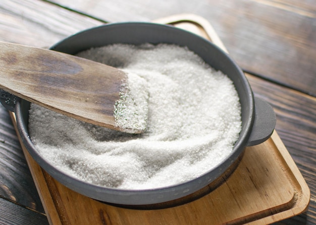 Castiron fry pan with salt on a wooden background Prepare the frying pan for first use