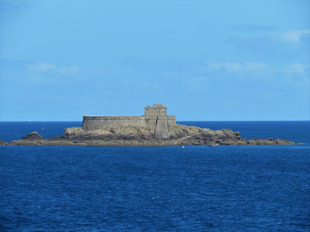 Castle by sea against blue sky