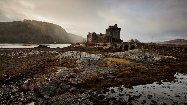 Photo castle on cliff against cloudy sky