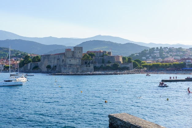 Castello in un porto medievale con barche e persone sulla spiaggia. concetto di viaggio