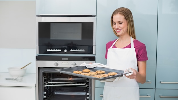 Casual blonde vrouw met bakplaat met cookies