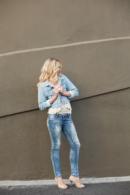 Повседневная блондинка в джинсовой одежде создает на открытом воздухе
