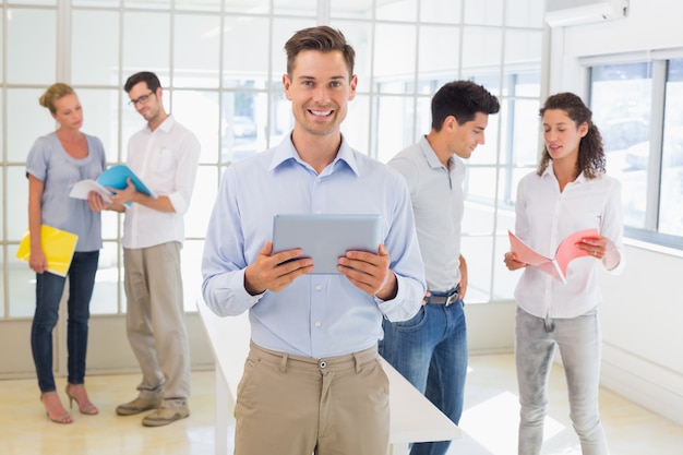 Casual boss smiling at camera in front of business team