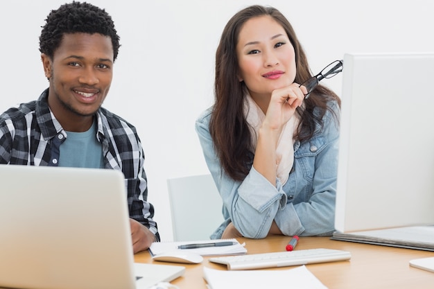 Casual business couple using computers in office