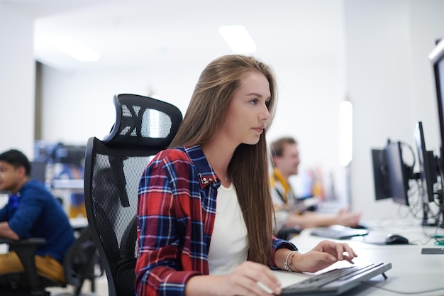 Casual business woman working on desktop computer in modern\
open plan startup office interior