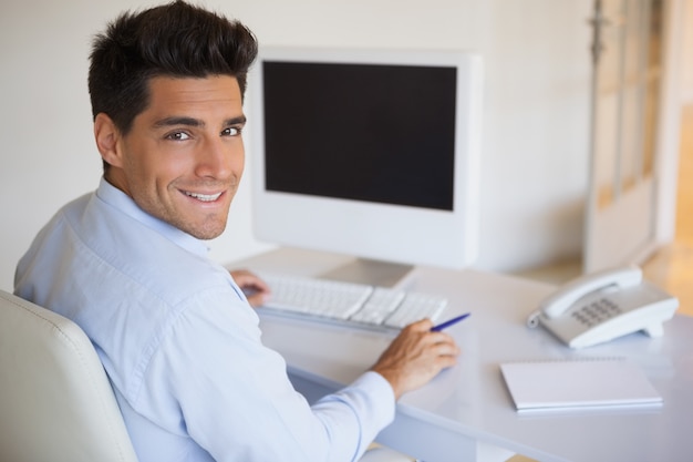 Casual businessman at desk smiling at camera