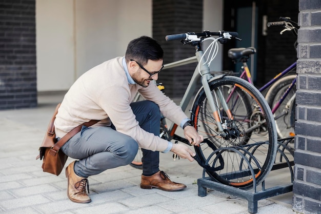 A casual businessman locks up his bicycle on the street