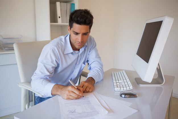 Casual businessman sitting at desk writing