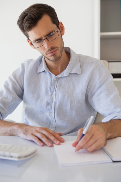 Casual businessman taking notes at his desk