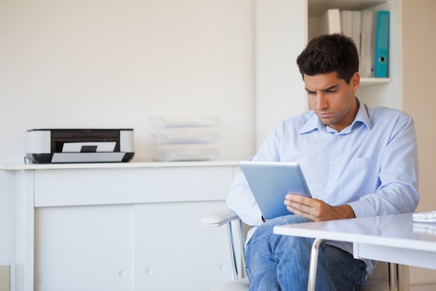 Photo casual businessman using his tablet at his desk